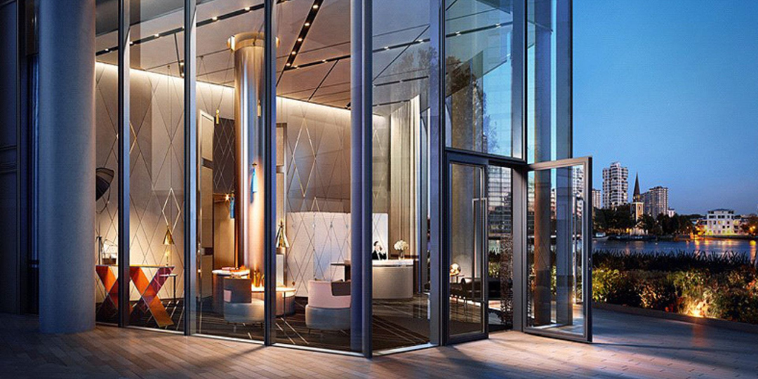 Modern luxury building with double-height glass entrance and architectural lighting, symbolising high-end construction standards in South West London.