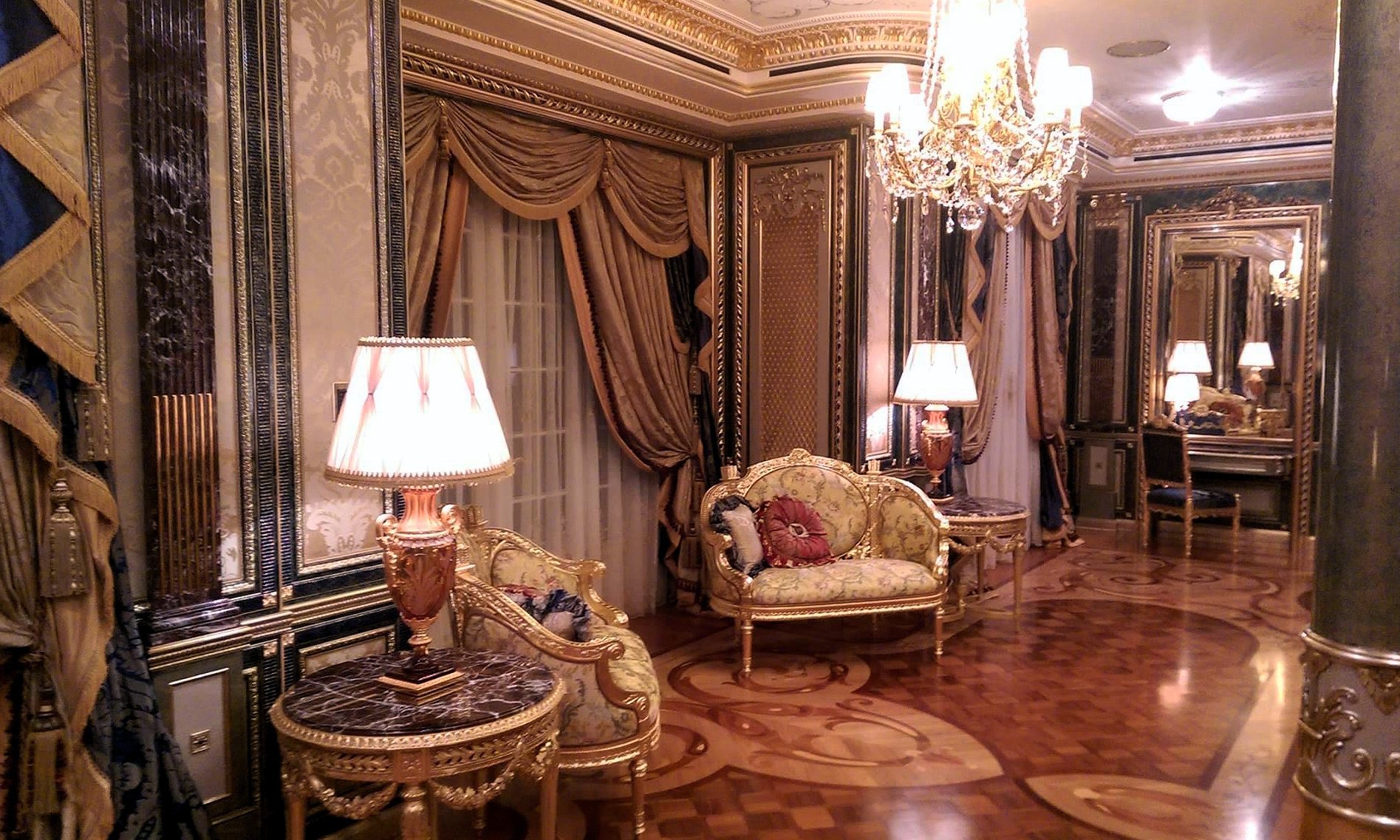 Opulent baroque-inspired living space with intricate gold detailing, luxury upholstery, and a crystal chandelier, perfect for bespoke interior projects.