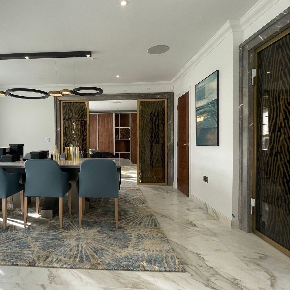 Modern dining room with bespoke blue chairs, large feature rug, and polished marble flooring.