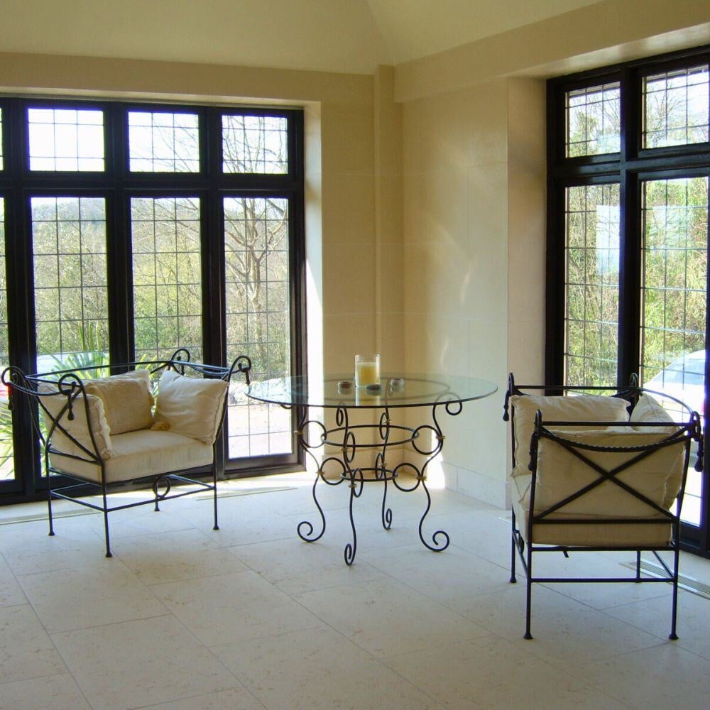 Elegant sunroom with wrought iron chairs and round glass table in Walton Place project.