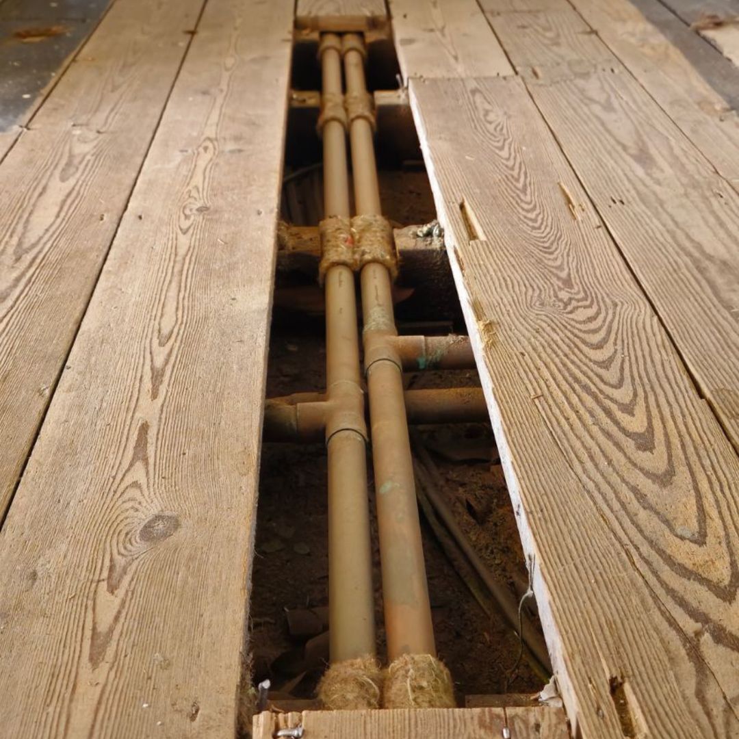 Timber floorboards removed to show pipe layout underneath during renovation