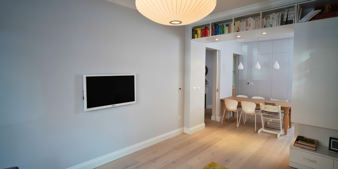Bespoke joinery in a modern London home featuring open-plan dining, built-in shelving, and light wood flooring.