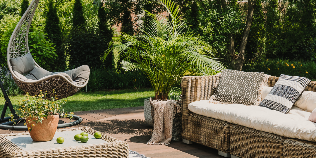 Stylish rattan garden furniture on a wooden patio with lush greenery in a UK summer garden.